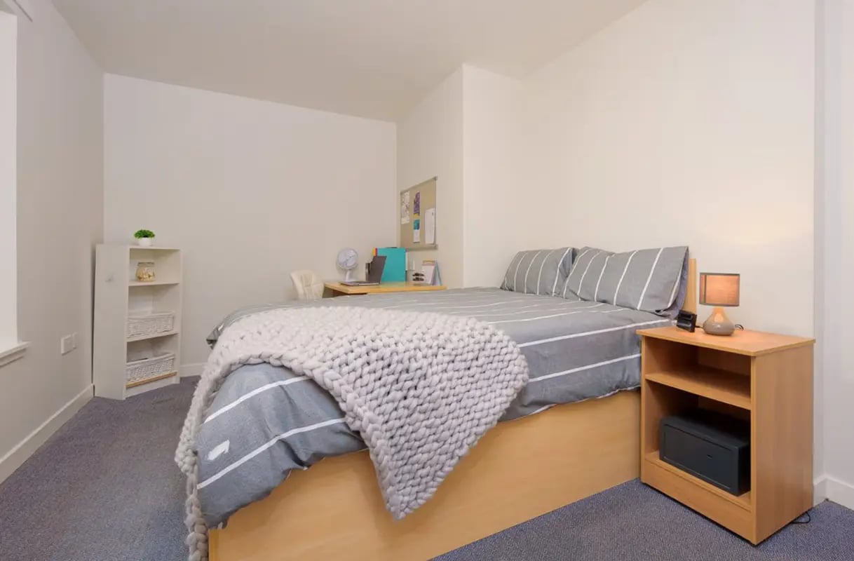 Bed with striped bedding desk fan and bookcase bedroom at Keiller Court in Dundee Student Accommodation